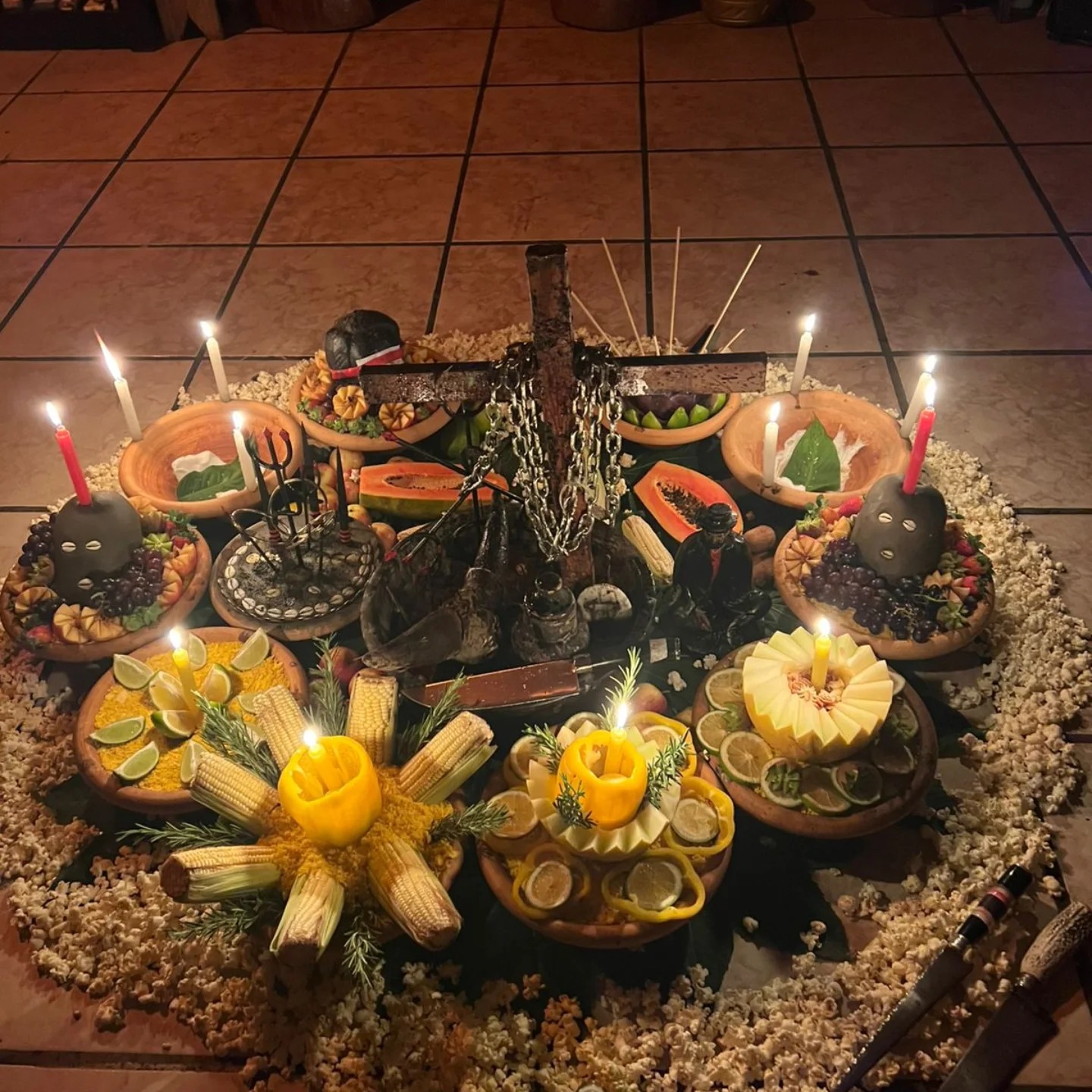 Mandala ritualística completa com oferendas, velas e cruz de Exu